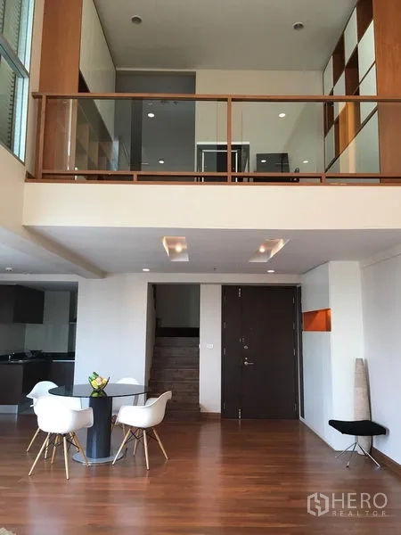 คอนโด ให้เช่าในPathum Wan, Bangkok - โถงพักผ่อนเพดานสูงสไตล์ลอฟต์ พร้อมชั้นลอย บันได และโต๊ะอาหาร