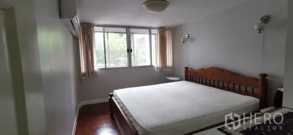 Townhouse for rent in Watthana, Bangkok - Bright bedroom with large windows, air conditioner and wooden bed frame
