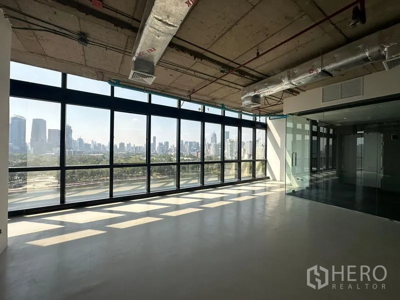 Office Space for rent in Watthana, Bangkok - Corner office area with panoramic windows, abundant natural light and a glass-walled meeting room overlooking the city.