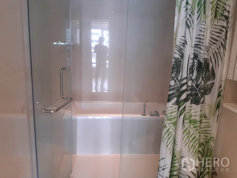 Condominium for rent in Watthana, Bangkok - Glass-enclosed bathtub and shower area with chrome fixtures.