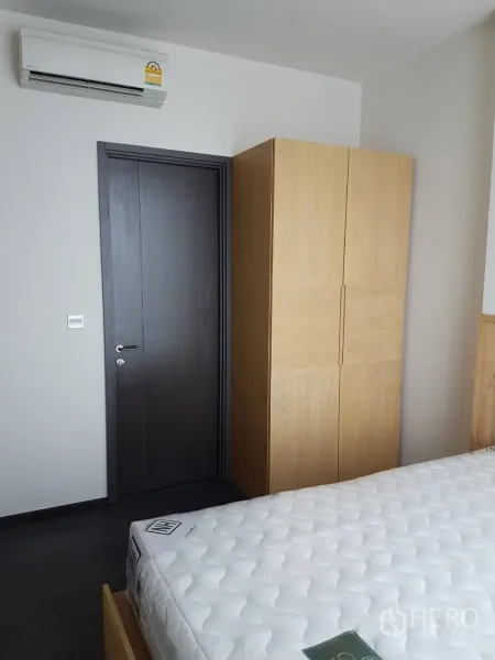 คอนโด ให้เช่าหรือขายในWatthana, Bangkok - มุมห้องนอนพร้อมตู้เสื้อผ้าไม้ เครื่องปรับอากาศ และที่นอนสีขาว