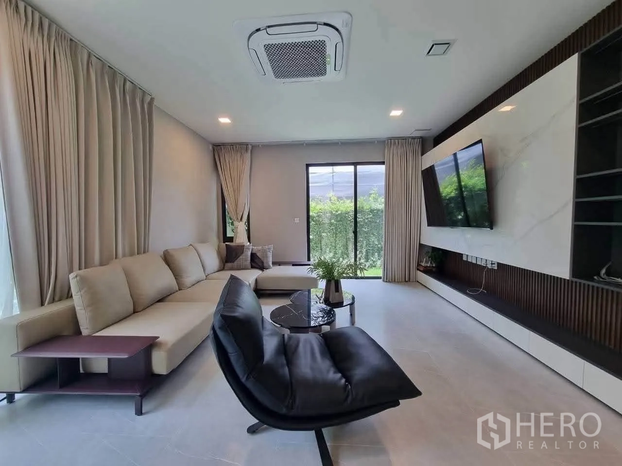 Detached House for rent in Bang Phli, Samut Prakan - Modern living room with L-shaped sofa, TV wall and sliding doors to garden.