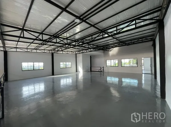 Warehouse for rent in Phra Samut Chedi, Samut Prakan - Spacious open-plan warehouse floor with steel trusses and daylight from windows.