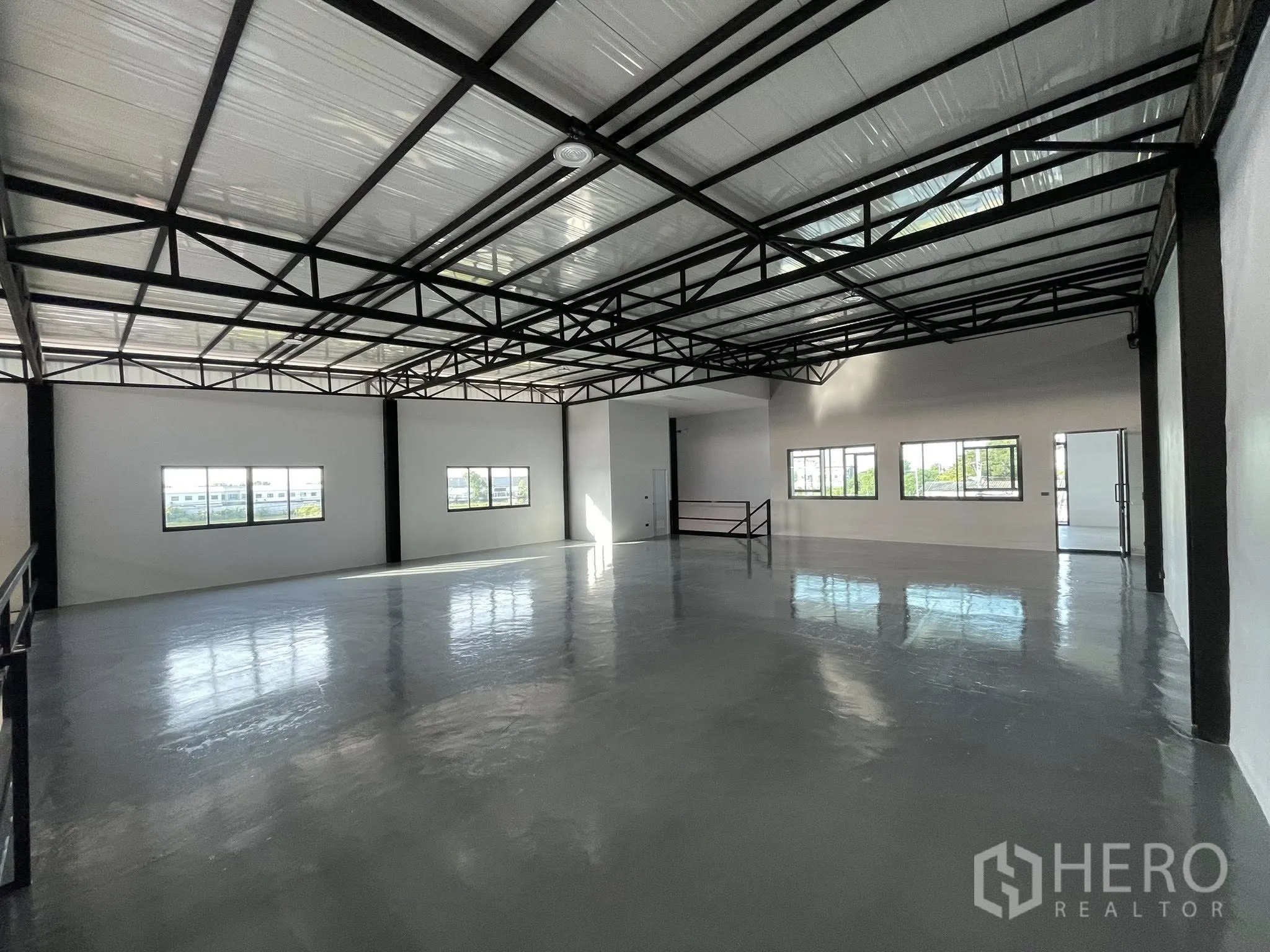 Warehouse for rent in Phra Samut Chedi, Samut Prakan - Spacious open-plan warehouse floor with steel trusses and daylight from windows.
