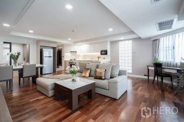 Apartment for rent - Spacious living area with sofa, study desk by the window and kitchen in view.