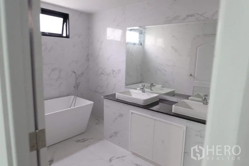 Detached House for sale in Bang Phli, Samut Prakan - White marble-style bathroom with freestanding tub and double vanity.