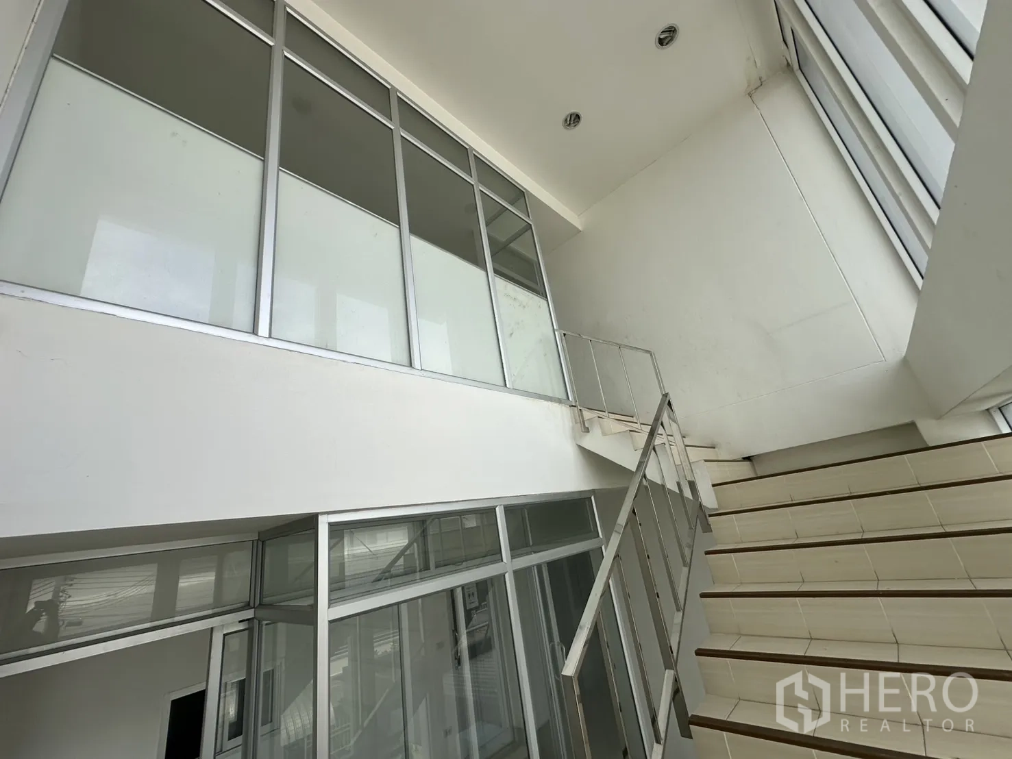 โรงงาน ให้เช่า - มุมมองบันไดขึ้นพร้อมผนังกระจกในอาคารสำนักงาน
