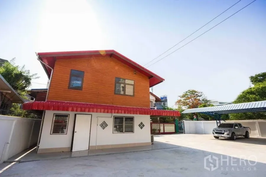 Home Office for rent in Watthana, Bangkok - Two-storey home office exterior with wood-clad upper level, large paved parking and steel-roof carport.