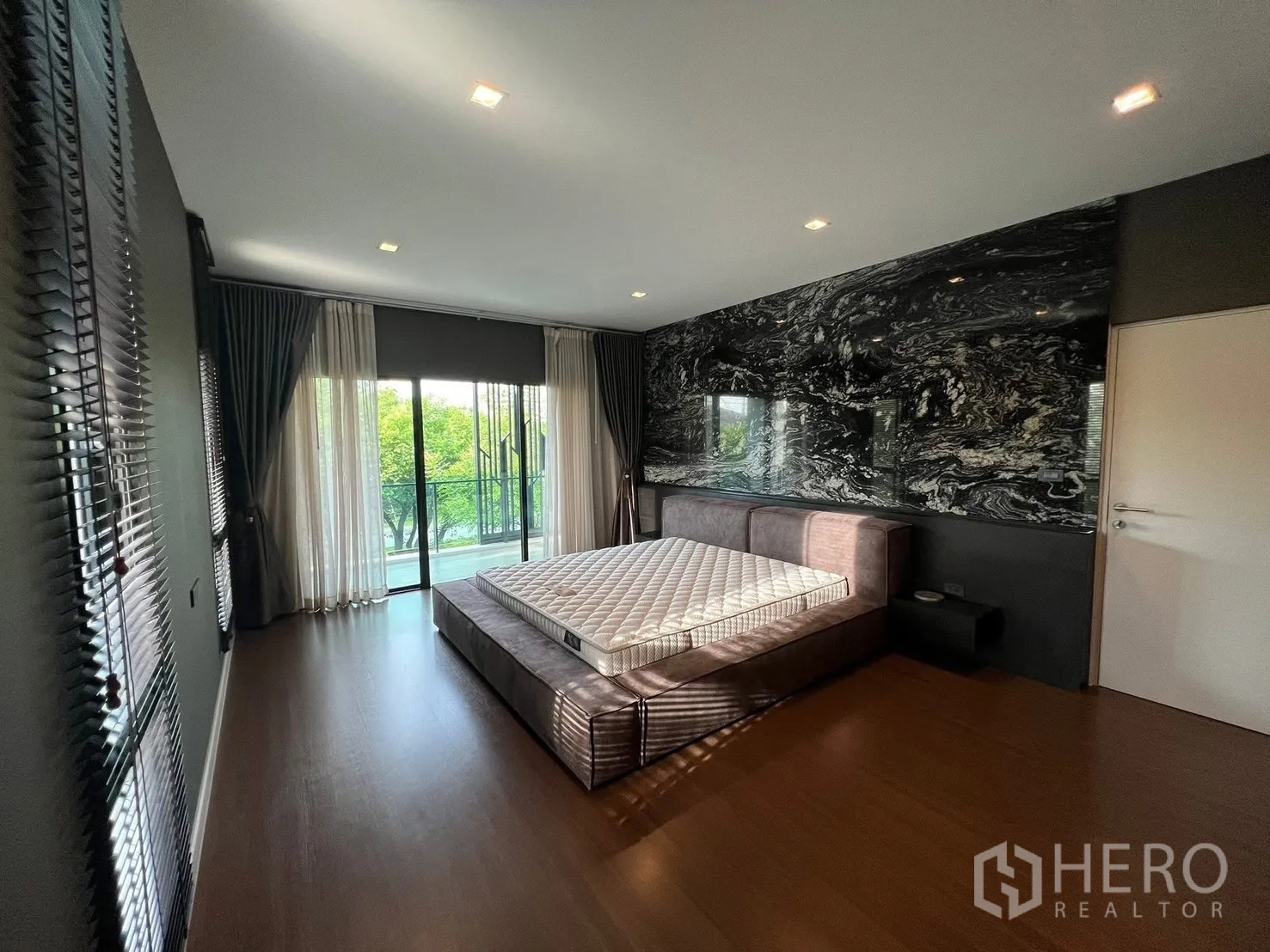 Detached House for rent in Bang Phli, Samut Prakan - Master bedroom angle featuring a striking black marble accent wall and balcony access through glass sliders.