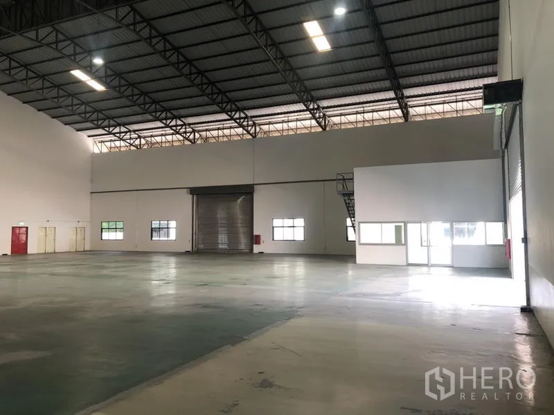 货栈 出租 - 宽阔仓库大厅，卷闸门、办公室模块及楼梯。