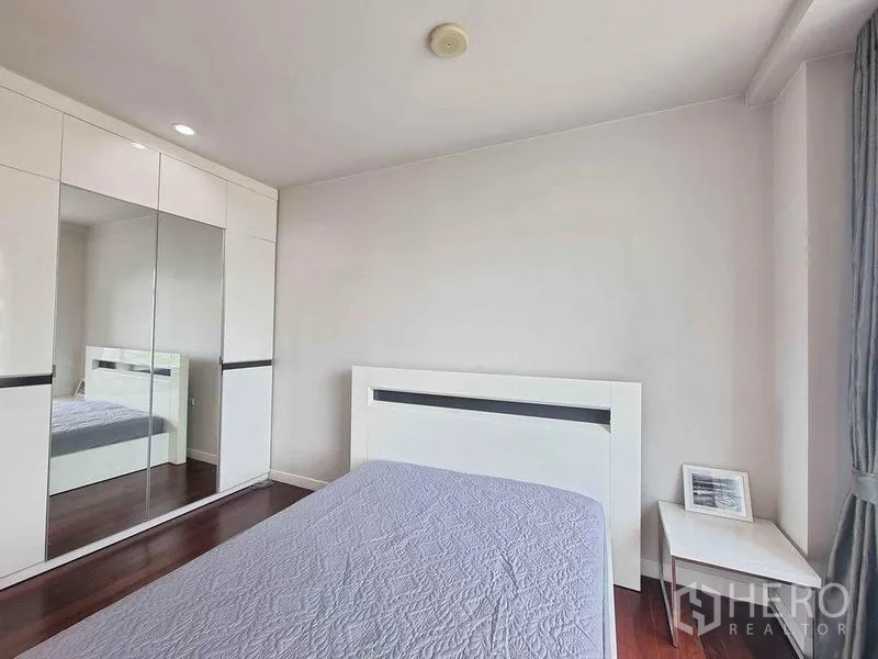 公寓 出租在Ratchathewi, Bangkok - 卧室配白色床架、镜面衣柜与窗边床头柜。
