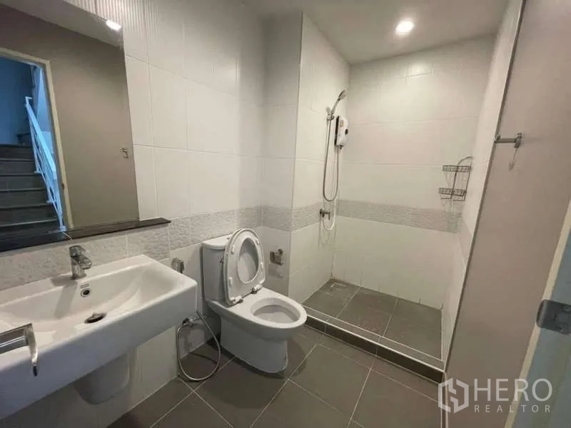 Townhouse for rent or sale in Phasi Charoen, Bangkok - Upstairs bathroom with walk-in shower, toilet and large mirror.