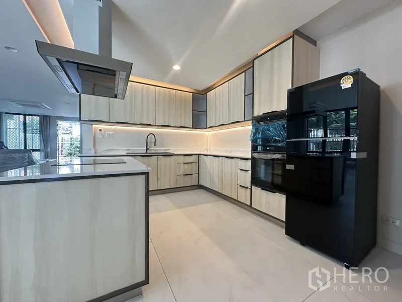 ทาวน์เฮาส์ ให้เช่าในWatthana, Bangkok - ครัวรูปตัวแอล ตู้ลายไม้ ตู้เย็นสีดำและเตาอบบิวท์อิน