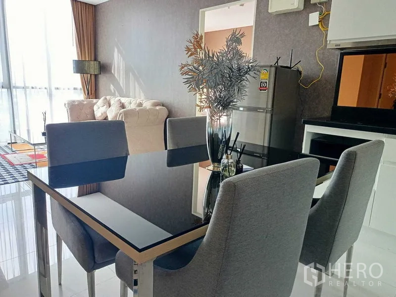 คอนโด ให้เช่าในWatthana, Bangkok - พื้นที่รับประทานอาหารแบบโอเพ่นแปลน โต๊ะกระจกสีดำ เก้าอี้ผ้าเทา ครัวขนาดกะทัดรัดและตู้เย็น เชื่อมต่อสู่ห้องนั่งเล่นที่มีหน้าต่างสูงโปร่ง.