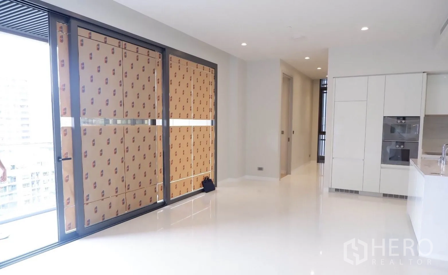 คอนโด ขายในWatthana, Bangkok - โถงนั่งเล่นเชื่อมครัวสีขาวพร้อมเตาอบบิลต์อิน และประตูบานเลื่อนออกระเบียง