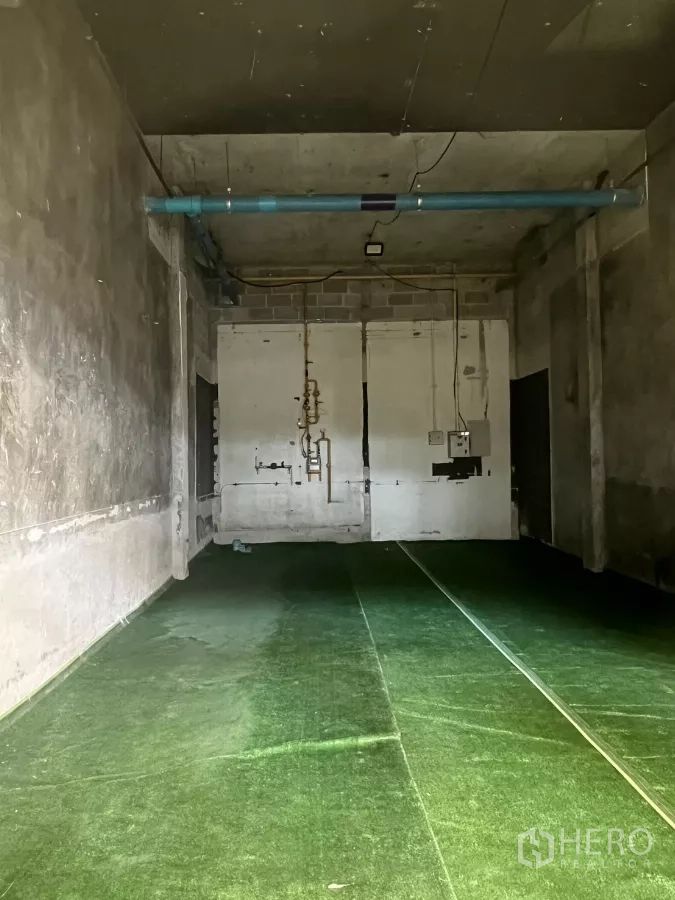 零售空间 出租 - 未装修的店内空间，层高较高，裸露管线与临时绿色地面，适合自定义装修。