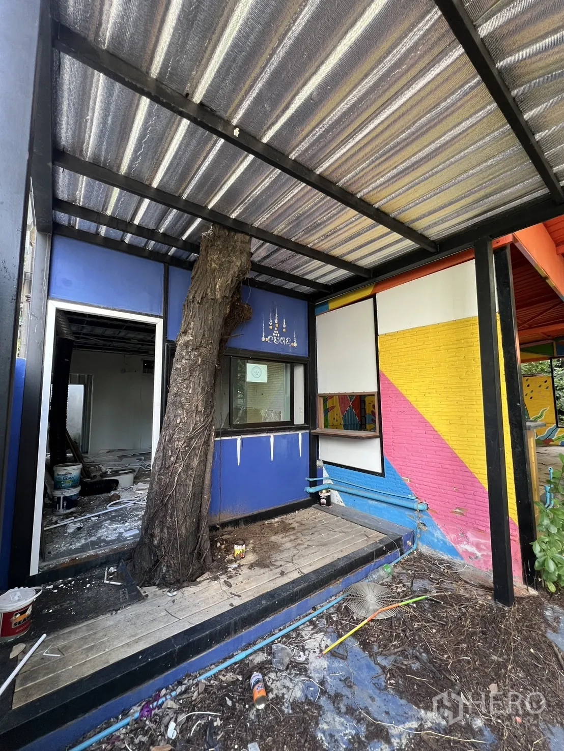 Detached House for rent in Watthana, Bangkok - Colorful shed and open shelter with debris in a leafy yard.
