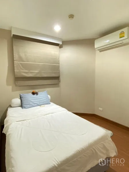Condominium for rent - Compact bedroom with single bed, wall air conditioner, and roman shade.