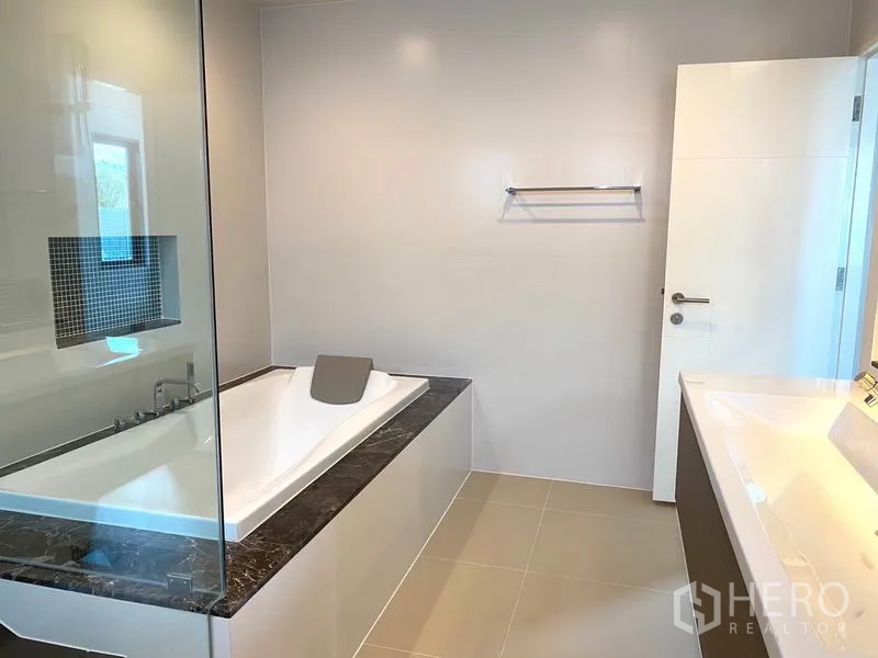 独立式住宅 出租在Saphan Sung, Bangkok - 现代浴室，内嵌式浴缸、玻璃隔断与瓷砖墙面。