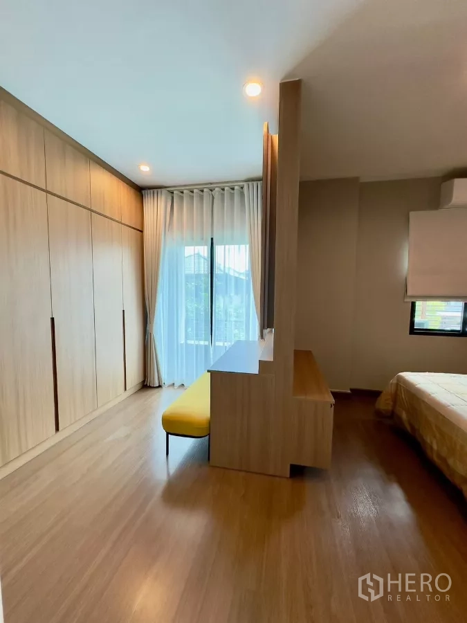 独立式住宅 出租在Samut Prakan - 更衣区配整面衣柜、阳台门与黄色长凳。