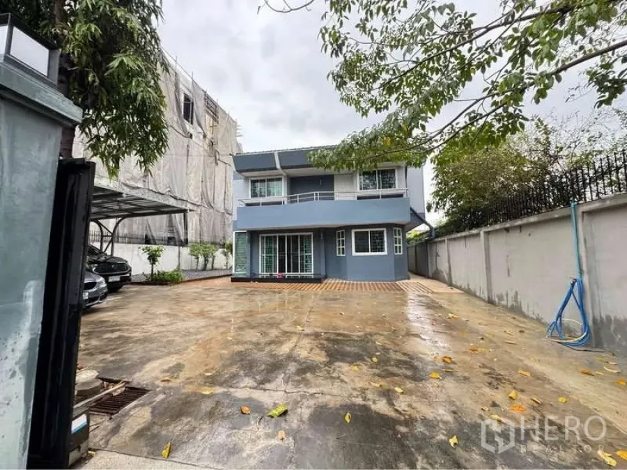 Detached House for rent in Suan Luang, Bangkok - Two-storey detached house with a wide concrete driveway, side carport and gated front yard.
