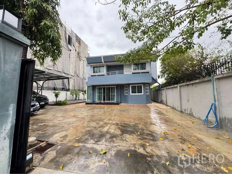Detached House for rent in Suan Luang, Bangkok - Two-storey detached house with a wide concrete driveway, side carport and gated front yard.