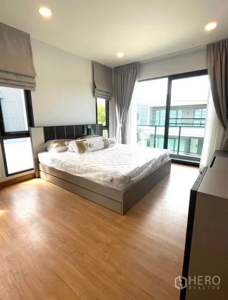 Detached House for rent - Primary bedroom on corner with wood flooring and floor-to-ceiling glass leading to the balcony.
