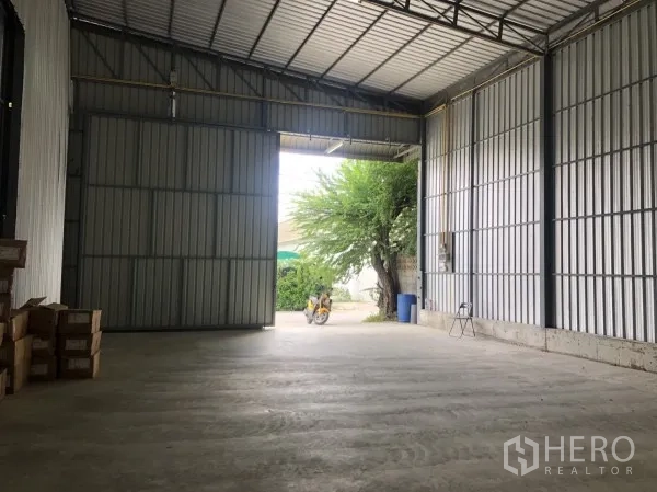 Warehouse for rent in Wang Thonglang, Bangkok - View from inside the warehouse toward the large entry doors and concrete floor.