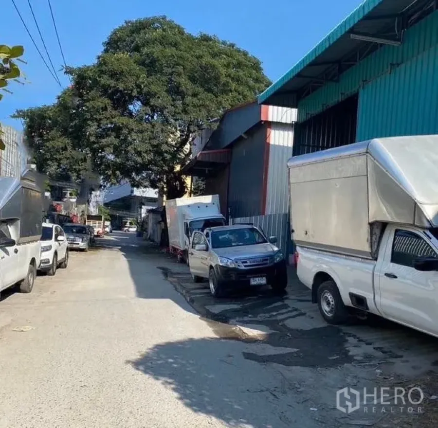 คลังสินค้า ให้เช่าในBang Kapi, Bangkok - มุมถนนหน้าโกดังผนังเมทัลชีทสีน้ำเงินในบางกะปิ มีรถกระบะจอด เหมาะสำหรับโหลดสินค้า
