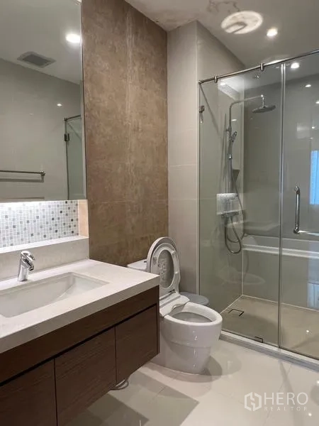 公寓 出租在Khlong Toei, Bangkok - 现代浴室，设洗手台、马桶与玻璃淋浴间，旁边为浴缸。