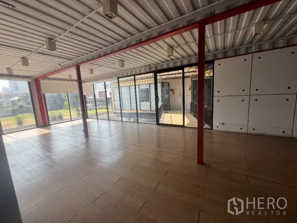 零售空间 出租在Watthana, Bangkok - 开放式零售空间，落地玻璃、木纹地砖与红色钢柱，景观视野通透。