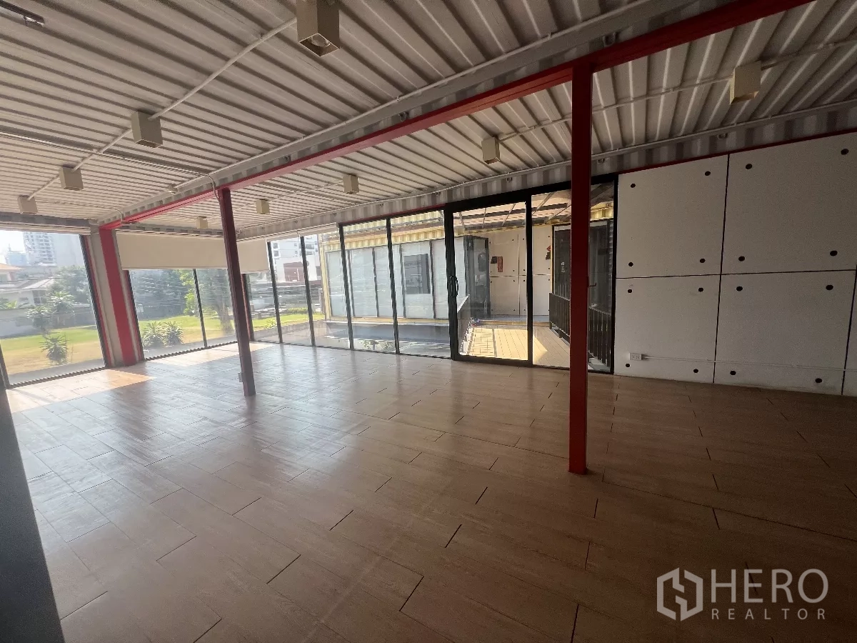 零售空间 出租在Watthana, Bangkok - 开放式零售空间，落地玻璃、木纹地砖与红色钢柱，景观视野通透。