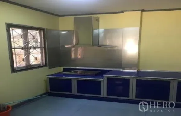Detached House for rent in Khlong Sam Wa, Bangkok - Functional Thai kitchen with a window, stainless backsplash, range hood and blue base cabinets.