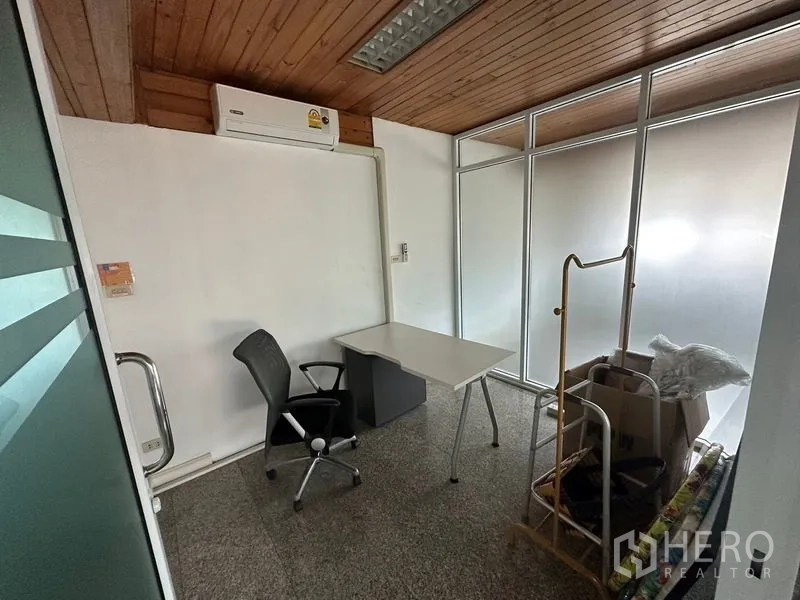 Office Space for rent - Compact workstation with desk and chair, frosted glass partition and wall-mounted air conditioner.