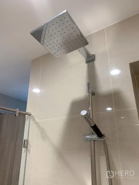 Condominium for sale in Bang Na, Bangkok - Square rainfall showerhead with handheld spray in a tiled shower area.
