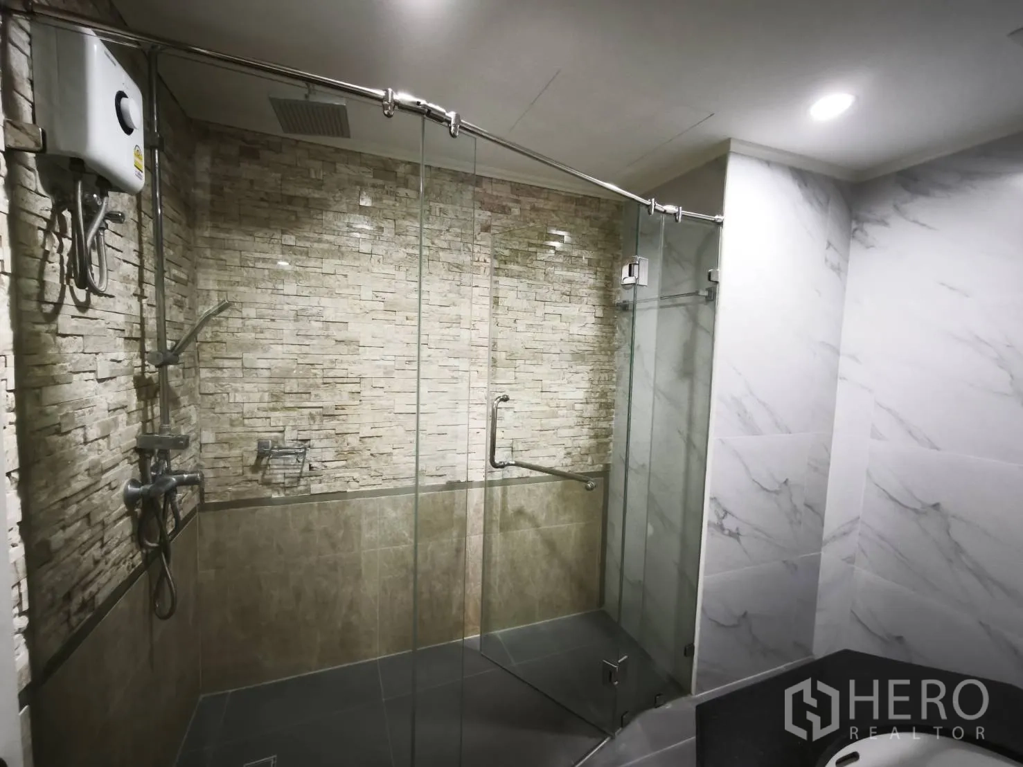 Condominium for rent in Watthana, Bangkok - Modern shower room with glass enclosure, rain shower, and stone accent wall.