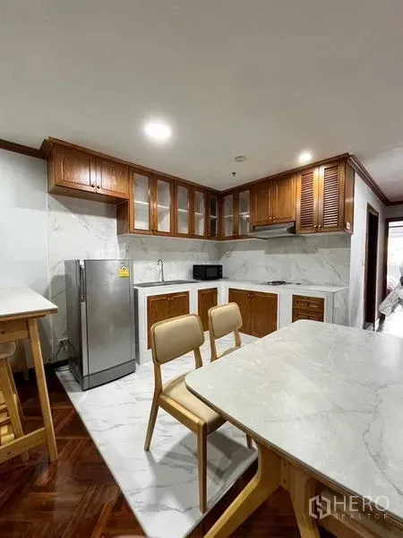 Condominium for rent in Ratchathewi, Bangkok - Separate kitchen featuring marble-look counters and backsplash, wooden cabinetry, stainless refrigerator and a dining set.