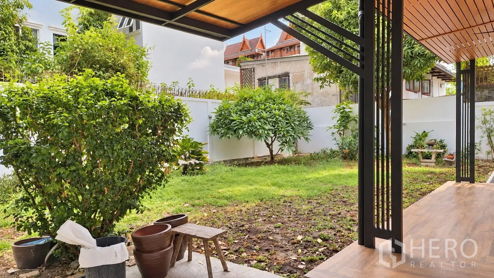 Detached House for rent in Khlong Toei, Bangkok - Covered terrace overlooking a green backyard with mature plants.