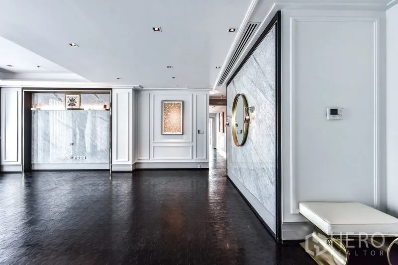 公寓 出租在Bang Rak, Bangkok - 大尺度客厅，白色墙板与圆形镜面装饰。