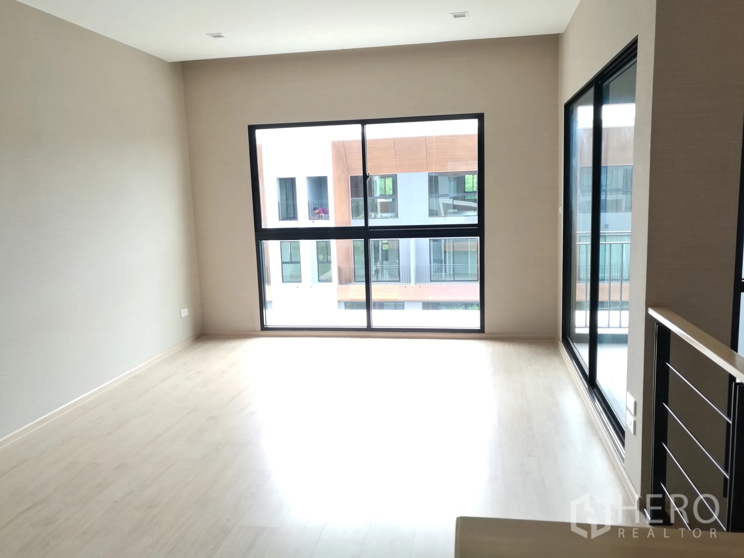 Townhouse for rent or sale in Suan Luang, Bangkok - Spacious upper floor room with large windows and balcony doors.