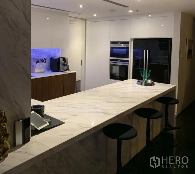 公寓 出售在Sathon, Bangkok - 厨房角度展示大理石岛台、内嵌烤箱与吧椅。