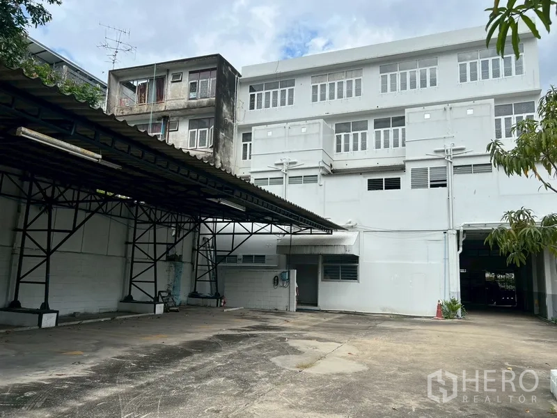 店屋 出租在Phra Khanong, Bangkok - 建筑后立面与宽阔停车区及雨棚。