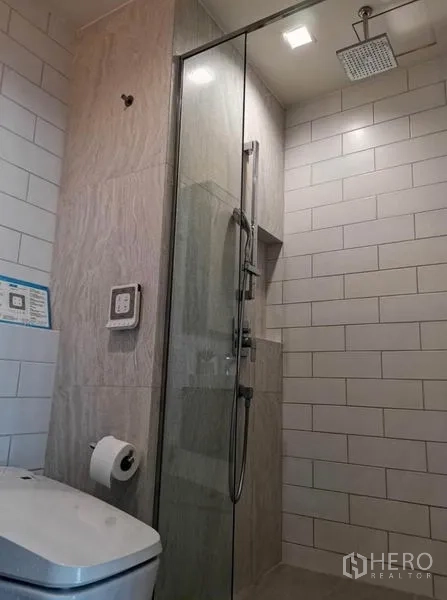 Condominium for rent - Modern bathroom with glass-enclosed rain shower and white subway tiles.