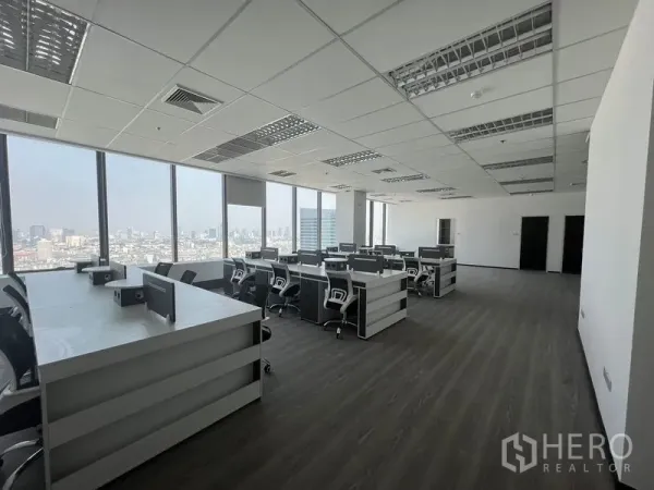 Office Space for rent in Huai Khwang, Bangkok - Open-plan workspace with bench desks and rolling chairs facing large windows and city views.