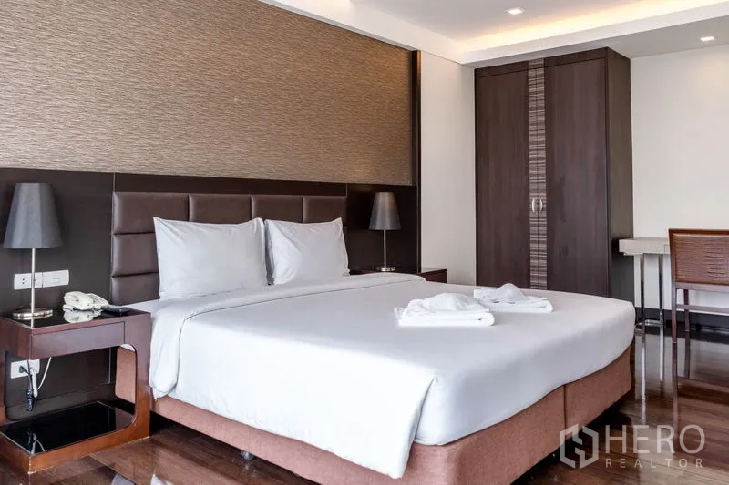 房间 出租在Khlong Toei, Bangkok - 主卧配特大床、软包床头、床头灯与衣柜。