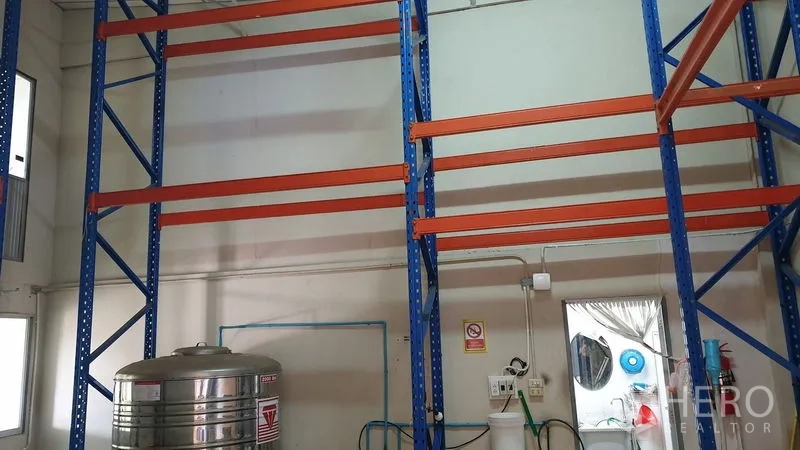 Warehouse for rent in Suan Luang, Bangkok - Tall blue and orange pallet racking with stainless tank and utilities inside a warehouse.