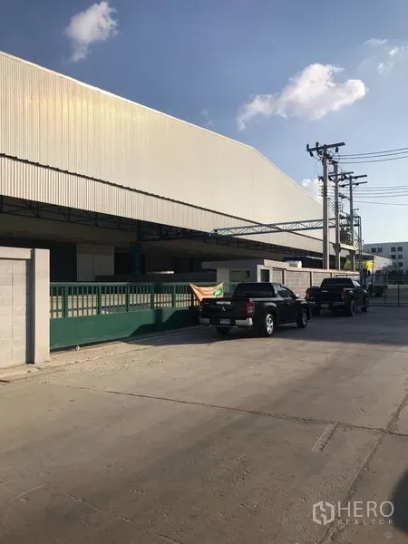 คลังสินค้า ให้เช่าในSamut Prakan - ด้านหน้าโกดังสมัยใหม่ ผนังเมทัลชีท ประตูรั้วปลอดภัย และลานโหลดมีหลังคา ในย่านบางเสาธง