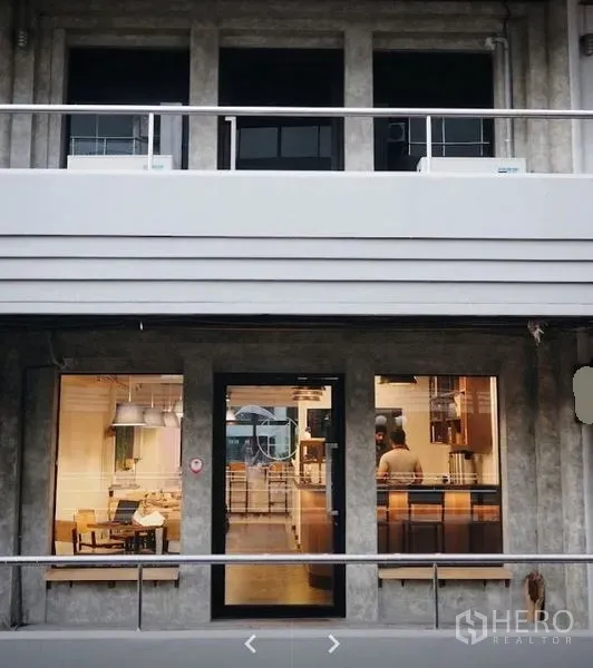 Retail Space for rent in Watthana, Bangkok - Modern concrete shopfront with glass door and large display windows glowing at night.