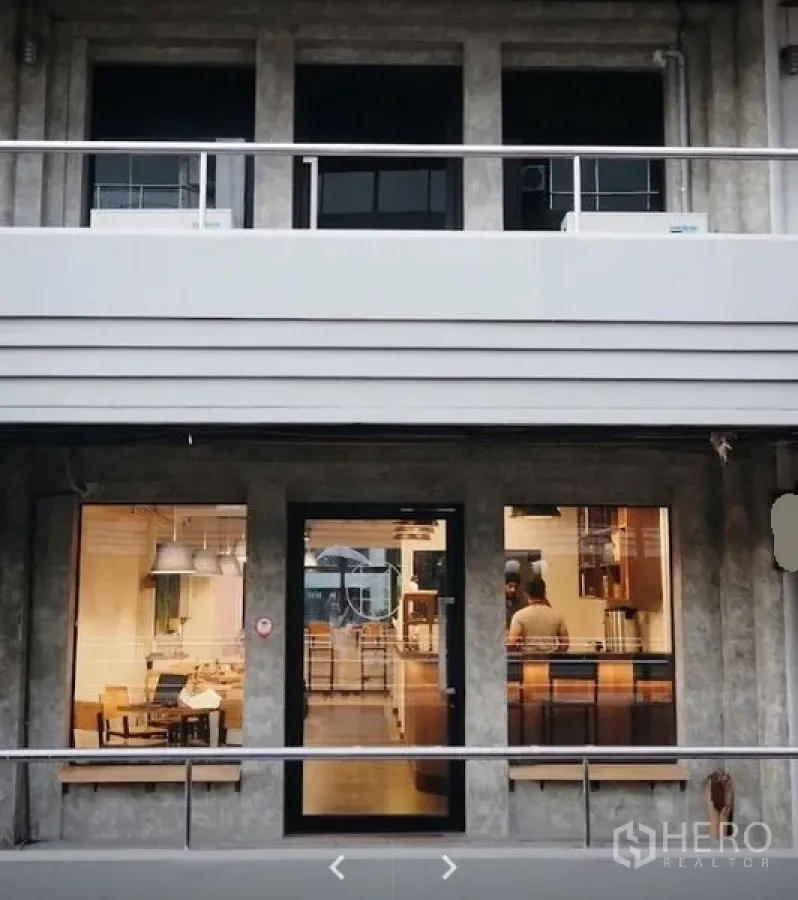 Retail Space for rent in Watthana, Bangkok - Modern concrete shopfront with glass door and large display windows glowing at night.