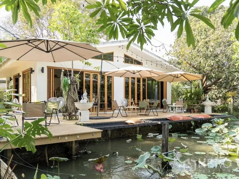 พื้นที่ขายปลีก ให้เช่าในSuan Luang, Bangkok - อาคารสีขาวสมัยใหม่ ประตูไม้บานใหญ่เปิดสู่เด็คริมบ่อบัว พร้อมร่มสนามและร่มไม้